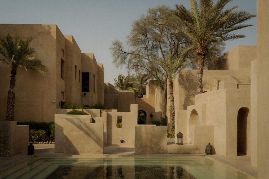 Courtyard with pool and palm trees in desert architecture.